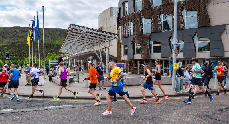 Runners running past Scottish Parliament in the Edinburgh Marathon 2023, Holyrood, Scotland, UK