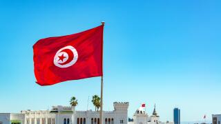 Tunisia flag waving in Tunis with government buildings in the background