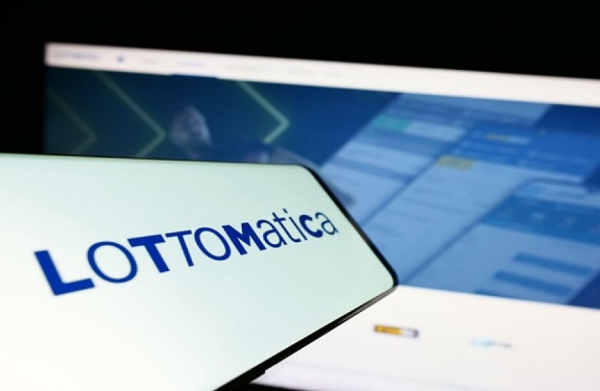 Cellphone with logo of Italian gambling company Lottomatica S.p.A. on screen in front of website. Focus on center-right of phone display.