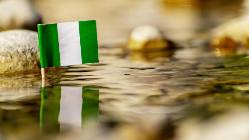 Nigeria flag reflected in the bright water of the stream