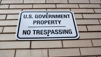 Annapolis, MD 08/21/2020: A white metal plate attached to a brick wall encircling a government building in Annapolis. The sign reads: 'U.S Government