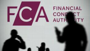 The FCA logo is seen on an LED screen in the background while a silhouetted person uses a smartphone in the foreground (Editorial use only)