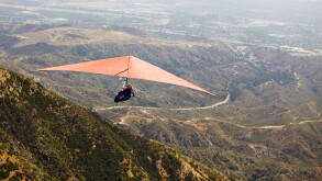 Man flying hang glider over valley