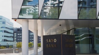 The Saxo Bank building at Tuborg Harbour, Hellerup in Copenhagen, Denmark. Surrounding buildings reflecting in the glass facade.