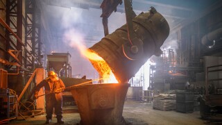 Steel worker and buckets of molten metal in steel foundry
