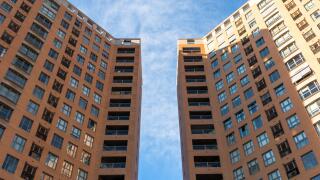 Low angle view of two symmetrical buildings of straight lines with a space between them with a blue sky above them. Architecture concept
