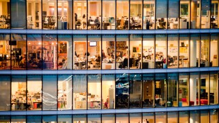 London, UK - February 2013: people work in a modern office building at dusk.