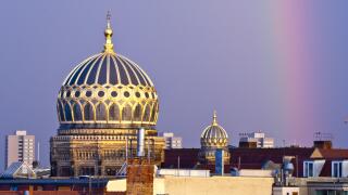 Berlin cathedral and synagogue domes in Berlin, Germany adorned with a rainbow after a summer storm.
