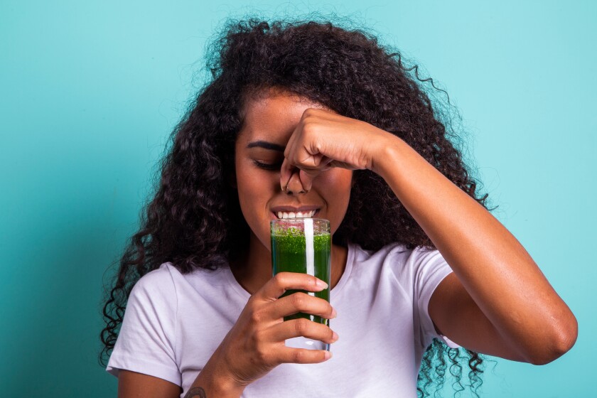 Disgusted africanwoman tasting a vegetable juice with bad flavor