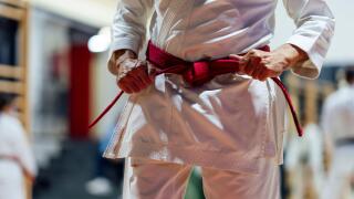 Active senior man tightening belt while practicing karate in class