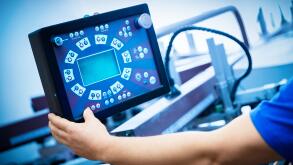 Worker programming print screening machine on the monitor. Industrial printer. Manufacture work.
