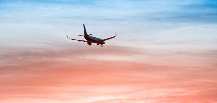 Large plane flies in the evening sunset sky, dramatic painted sky and airplane silhouette with clouds over Lisbon in Portugal