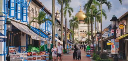 View of colorful Muscat St., lined with traditional shophouses, and Sultan Mosque in Kampong Glam, Singapore; with Asian and Western tourists visiting
