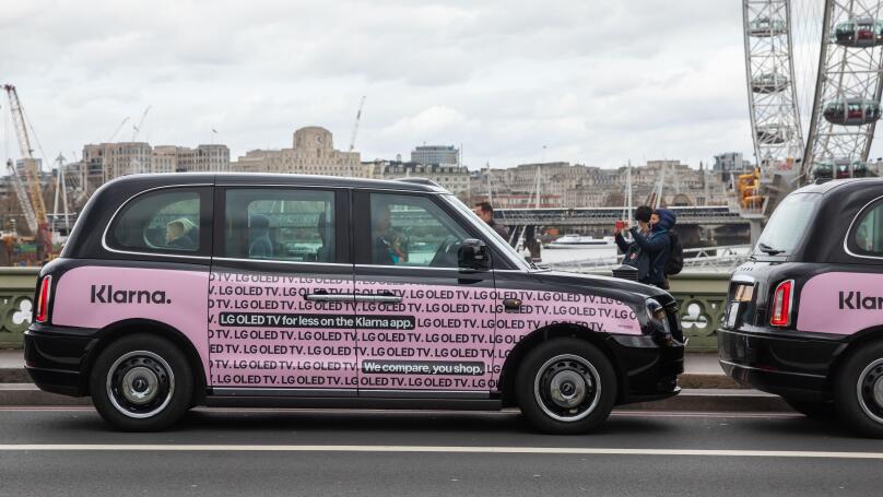 Black taxis with pink Klarna poster in Westminster London, UK