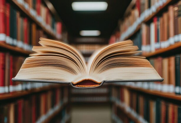 Books floating in the air featuring bookshelves and surrealism concept. An open book floating in a library filled with bookshelves.