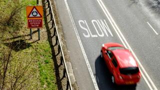 Speeding car approaching warning to slow down, on UK road