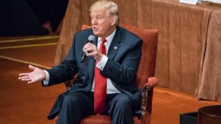 Donald Trump is seated answering questions at the Economic Club of New York.
