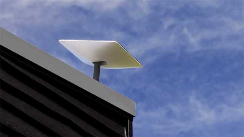 Starlink Premium antenna atop a roof against a blue sky