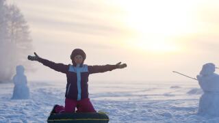 Happy girl enjoying winter activity at frozen lake and winter forest