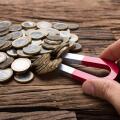 Cropped image of businessman's hand pulling coins with magnet on wooden table