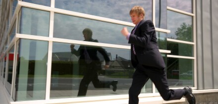 A Stock Photograph of a Young Adult Businessman Outside a Modern Office Block Running