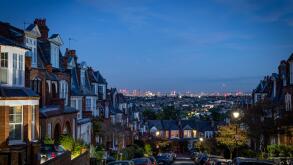 A night time view over London showing terraced houses and London skyline towards the City.This illustrates the housing market to great creative effect
