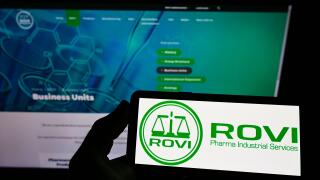 Person holding smartphone with logo of company Laboratorios Farmaceuticos Rovi S.A. on screen in front of website. Focus on phone display.