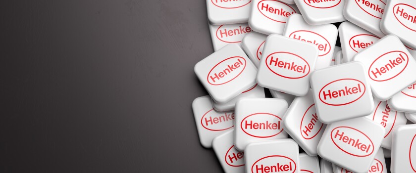 Logos of the German chemical and consumer goods company Henkel on a heap on a table. Copy space. Web banner format.