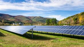 Rows of solar panels in a field in the Mountains on a sunny autumn day