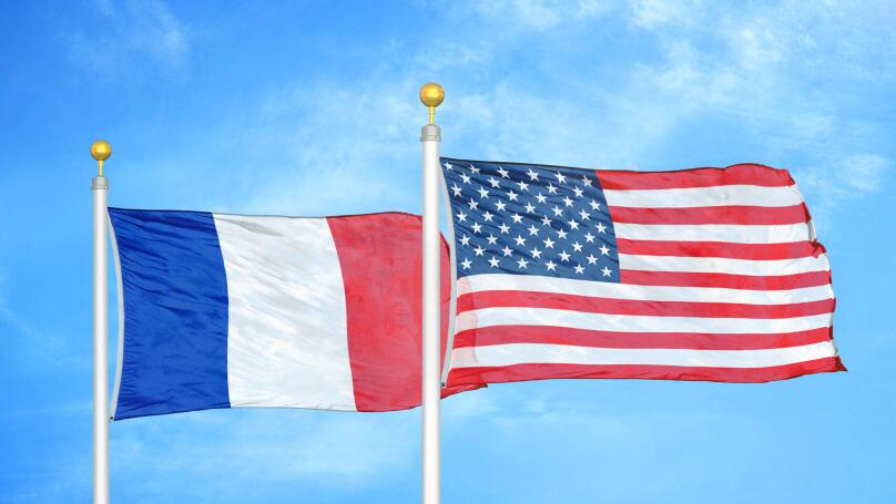 France and United States two flags on flagpoles and blue cloudy sky
