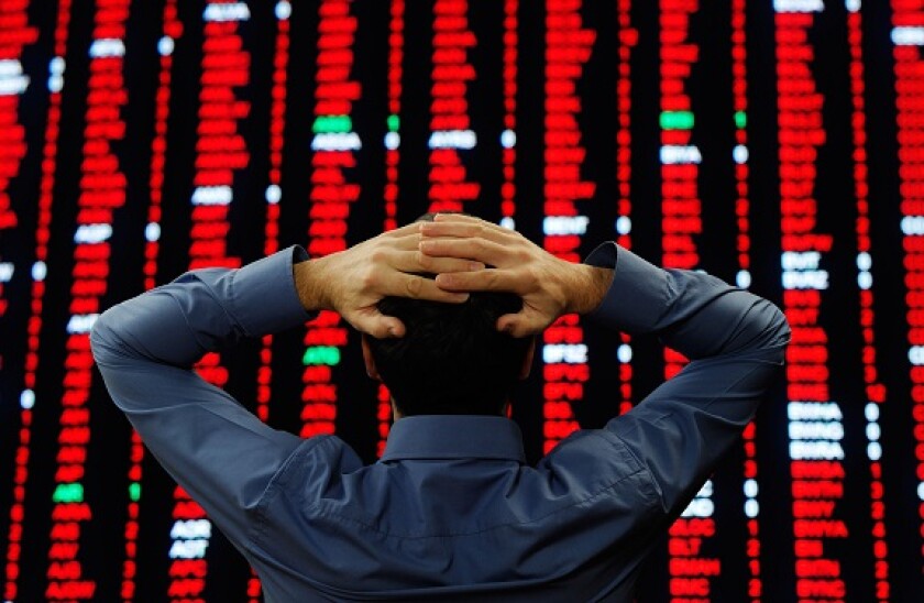 Stock Trader Stood in Front of a Large Display of Stock Prices