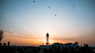montjuic cableway tower at dawn with sun rising behind tower during sunrise with spectacular rays, a landmark of barcelona with the port and cruise sh