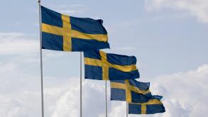 Row of Swedish flag poles against cloudy sky