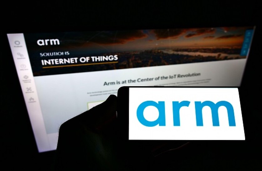 Person holding smartphone with logo of British semiconductor company Arm Ltd. on screen in front of website. Focus on phone display.