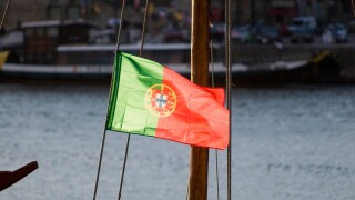 Backlit Portuguese flag flying from the mast of a wine barge, Porto, Portugal.