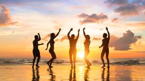 Group of happy people having fun dancing at a beach party, summer vacation, full moon, Thailand