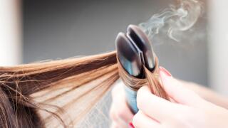 Hairdresser Applying a Straight Iron on a Woman Hairdo