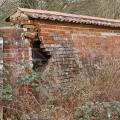 a crumbling red brick wall around a farm yard in need of repair
