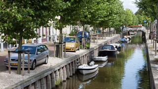 Canal with boats and cars parked alongside in residential area of Harlingen Friesland Netherlands
