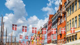 Danish flags and colorful buildings in Nyhavn, Copenhagen in Denmark.