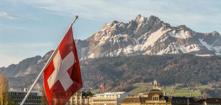 Swiss National Flag in Lucerne in Central Switzerland with the mountain range of Mt Pilatus in the background