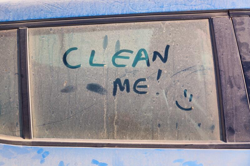The inscription Clean me on a dirty car with a smile.