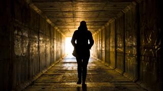 Female figure walking toward the light at the end of the tunnel