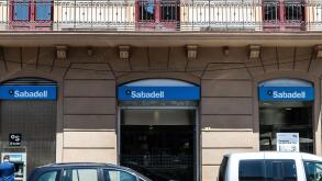 Tortosa, Spain - May 13, 2022: Facade and logo of the Banco Sabadell with people at the ATM in Tortosa, Catalonia, Spain
