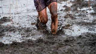 Mud race runner, man running in mud. Runners during extreme obstacle races. Active life and sport concept