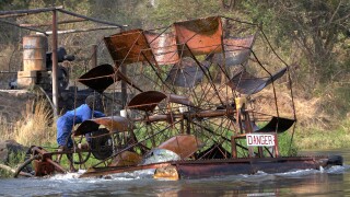 Worker operating a floating waterwheel on the Lower Zambezi River Zambia Zimbabwe Africa