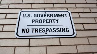 Annapolis, MD 08/21/2020: A white metal plate attached to a brick wall encircling a government building in Annapolis. The sign reads: 'U.S Government