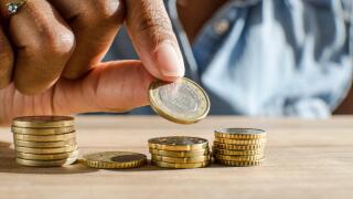Closeup of a black woman hand counting Euro coins on a wooden table. Selective focus,