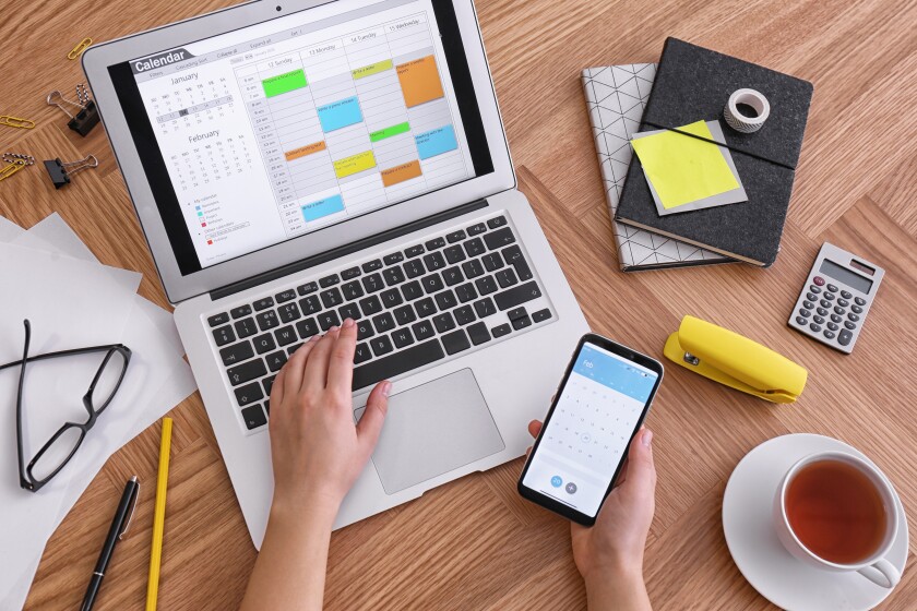 calendar on laptop and smartphone at wooden table-adobe-2022