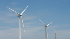 Three wind turbines, close-up of blades, against blue sky. Wind power "wind farm" turbines alternative energy, renwable energy.